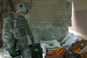 Marcus Griffin, an anthropologist working for the 101st Airborne Division’s 2nd Brigade Combat Team, inspects a fruit stand in Ghazaliyah, Iraq, while on patrol Jan. 13, 2008. Griffin is helping soldiers better understand the needs of the Iraqi people. (U.S. Army photo by Sgt. James P. Hunter, USA/Released)