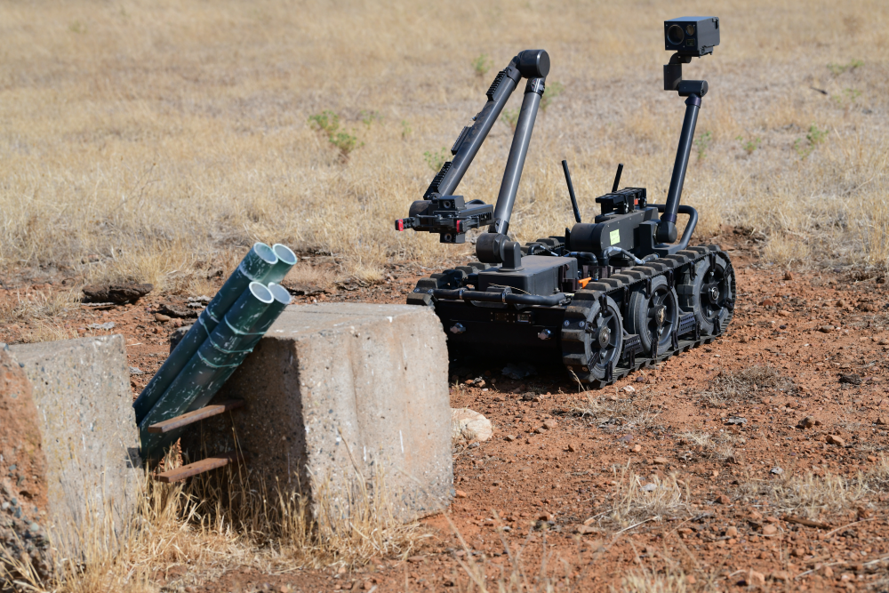 A man-portable tracked robot investigates a suspicious object.
