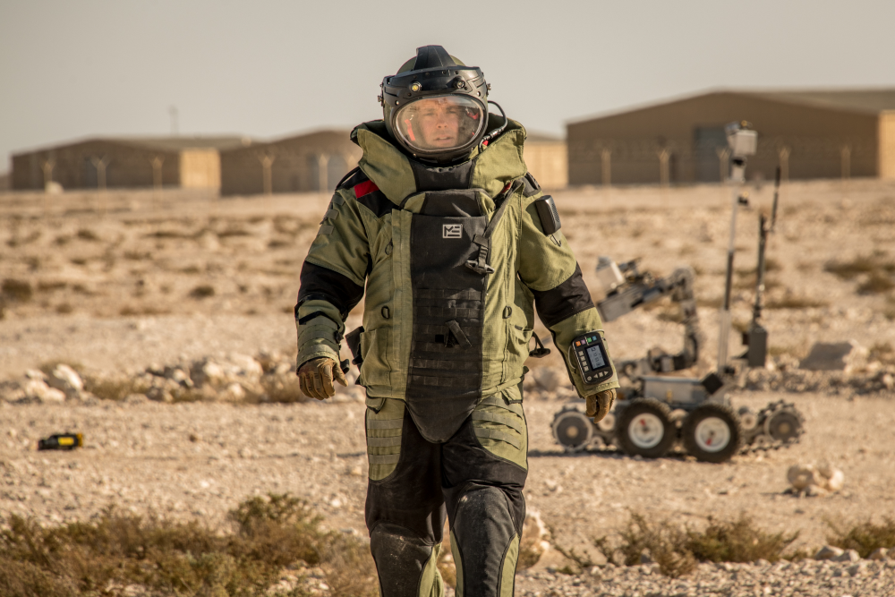 Explosive Ordnance Disposal personnel suited up in a desert landscape.