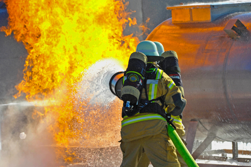 Two firefighters spraying fluid onto a fire in a training exercise