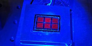 The record-setting solar cell shines red under blue luminescence (photo by Wayne Hicks, NREL).