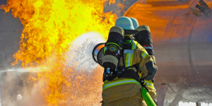 Two firefighters spraying fluid onto a fire in a training exercise