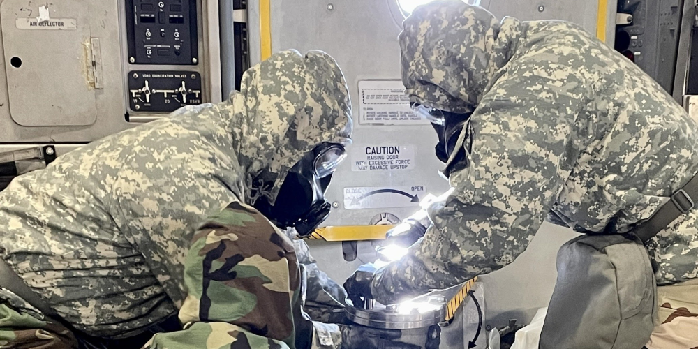 Military Personnel with protective equipment hold a container